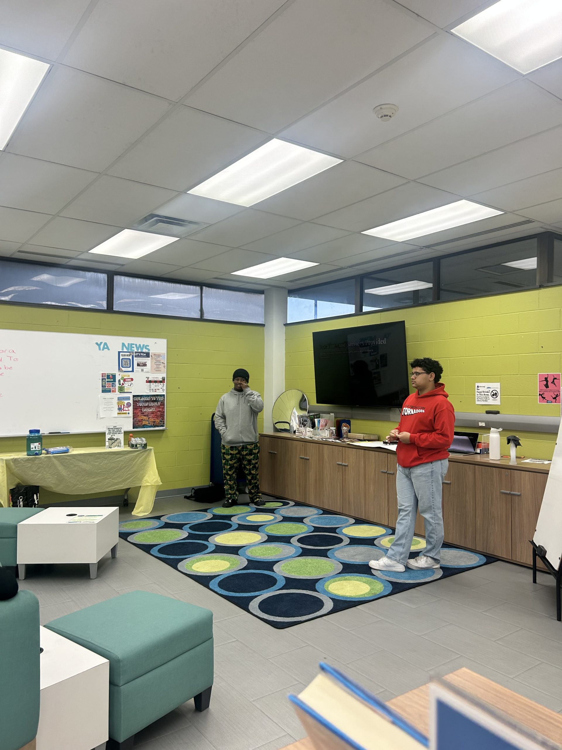 Two students engage in a discussion in a colorful classroom setting